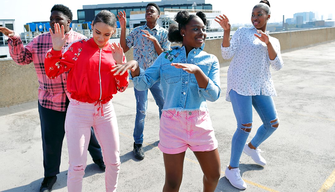 A imagem mostra um grupo de jovens com meninas e meninos dançando. 